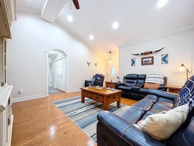 living room featuring ceiling fan, light hardwood / wood-style floors, ornamental molding, and vaulted ceiling