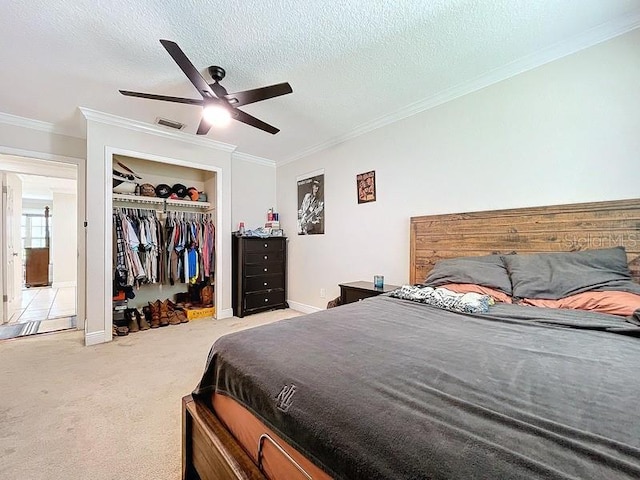 bedroom featuring ornamental molding, a textured ceiling, light colored carpet, ceiling fan, and a closet