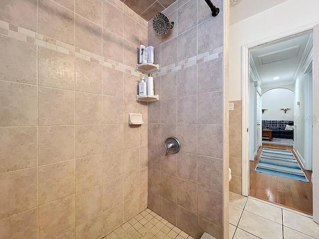 bathroom featuring tile patterned floors, toilet, a tile shower, and crown molding