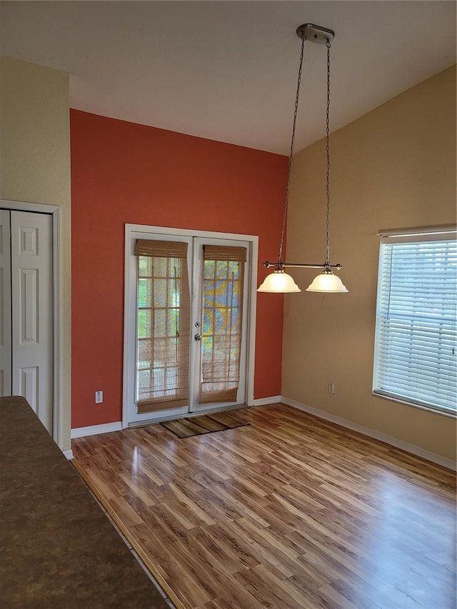 unfurnished dining area featuring french doors, hardwood / wood-style floors, and lofted ceiling