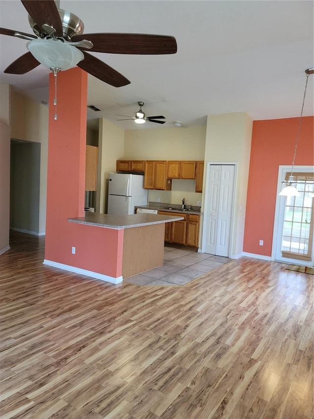 kitchen featuring kitchen peninsula, pendant lighting, white fridge, and light hardwood / wood-style floors