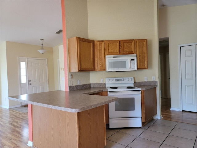 kitchen with kitchen peninsula, white appliances, high vaulted ceiling, and hanging light fixtures