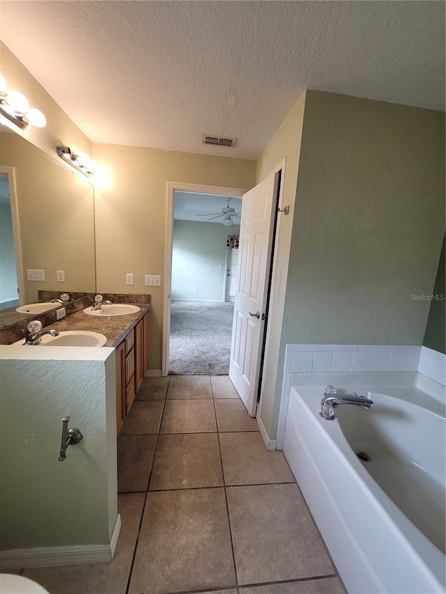 bathroom featuring tile patterned floors, vanity, a textured ceiling, ceiling fan, and a bath