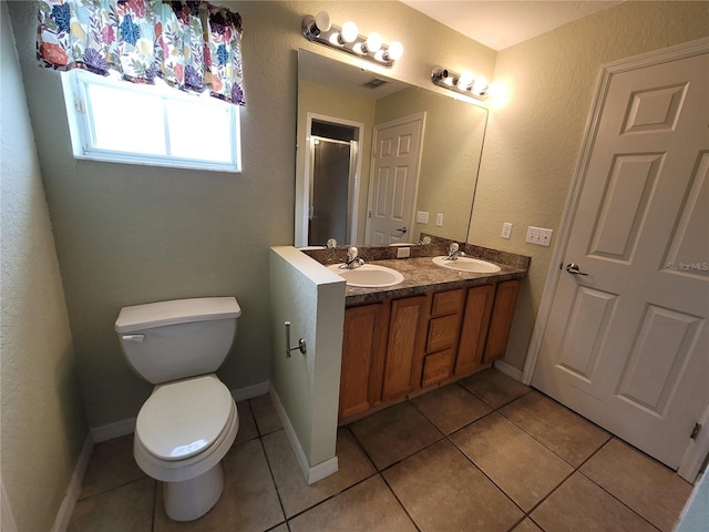 bathroom with toilet, vanity, tile patterned floors, and a shower with shower door