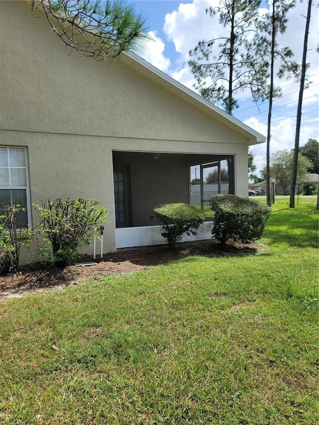 view of home's exterior featuring a sunroom and a yard