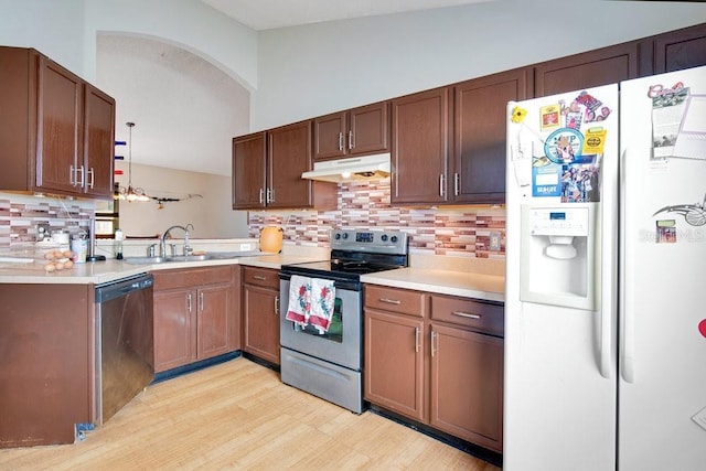 kitchen with appliances with stainless steel finishes, lofted ceiling, tasteful backsplash, light hardwood / wood-style floors, and sink