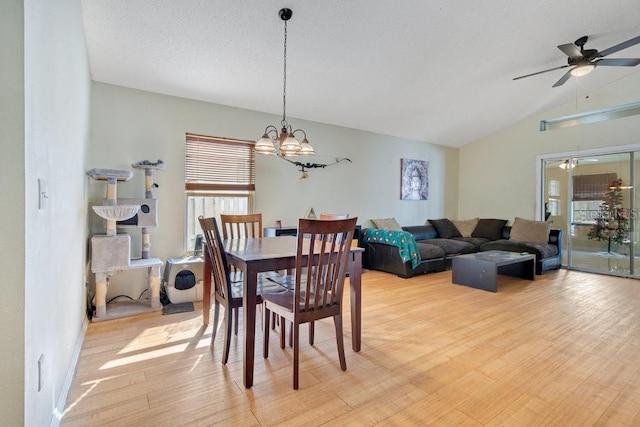 dining area with vaulted ceiling, a textured ceiling, light hardwood / wood-style floors, and ceiling fan with notable chandelier