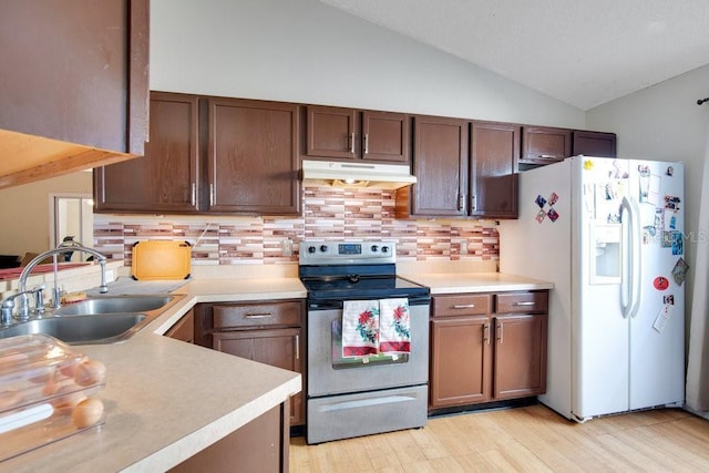 kitchen with lofted ceiling, tasteful backsplash, sink, white refrigerator with ice dispenser, and stainless steel range with electric stovetop