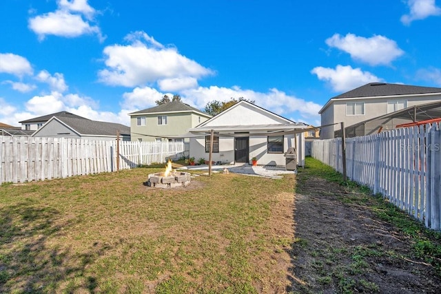 back of house with a yard and a fire pit