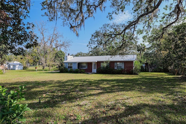 single story home featuring a front yard and a storage unit