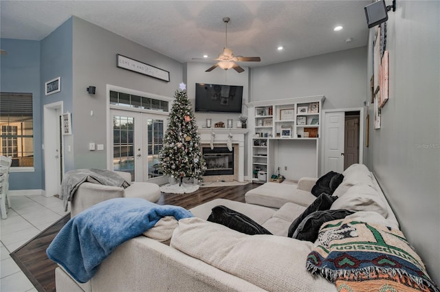 tiled living room with a towering ceiling, french doors, a textured ceiling, and ceiling fan