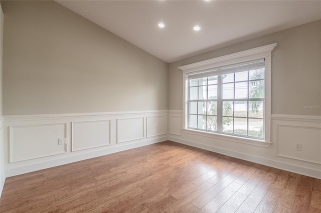 empty room featuring plenty of natural light, light wood-type flooring, and vaulted ceiling