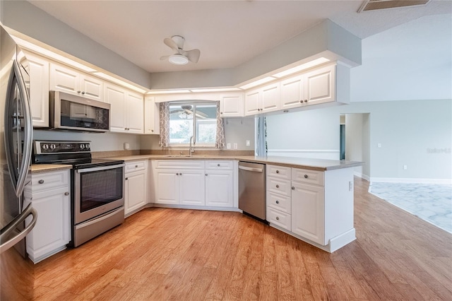 kitchen with kitchen peninsula, stainless steel appliances, sink, light hardwood / wood-style floors, and white cabinetry