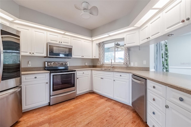 kitchen featuring white cabinets, sink, light wood-type flooring, kitchen peninsula, and stainless steel appliances