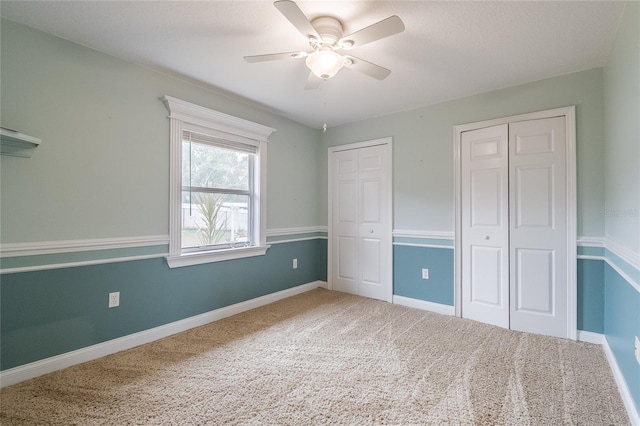 unfurnished bedroom featuring multiple closets, ceiling fan, and carpet floors