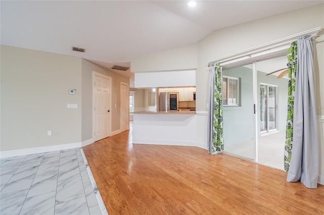 unfurnished living room featuring vaulted ceiling and light wood-type flooring