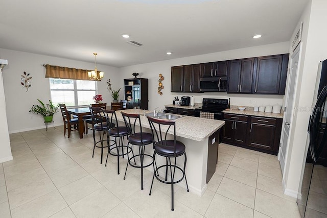 kitchen with sink, hanging light fixtures, black / electric stove, a breakfast bar area, and a center island with sink