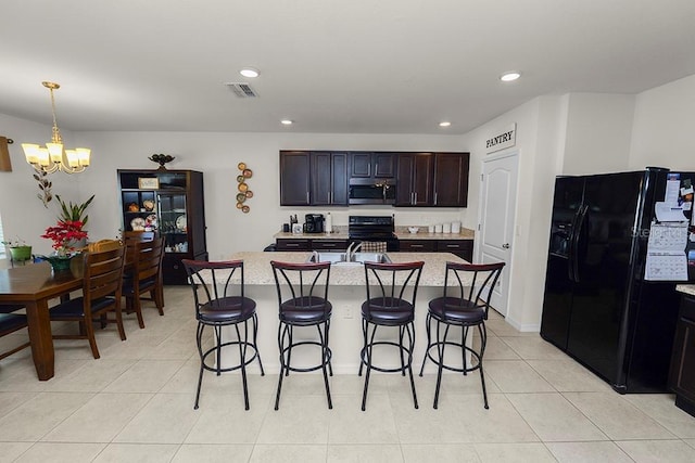 kitchen with black appliances, a notable chandelier, dark brown cabinetry, and an island with sink