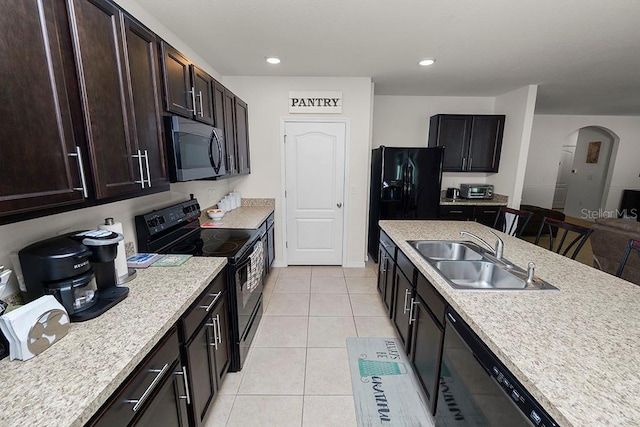 kitchen featuring dark brown cabinetry, sink, light tile patterned flooring, and black appliances