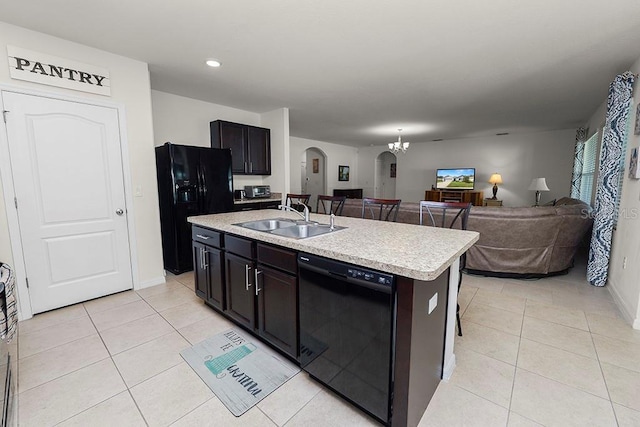 kitchen featuring sink, black appliances, a center island with sink, a notable chandelier, and light tile patterned flooring