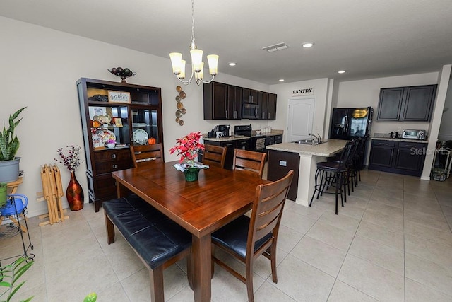 dining space with light tile patterned floors, a notable chandelier, and sink