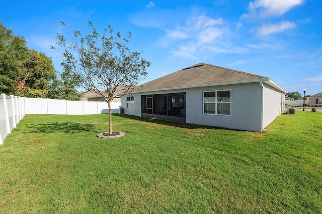 rear view of house featuring a lawn, a sunroom, and central AC unit