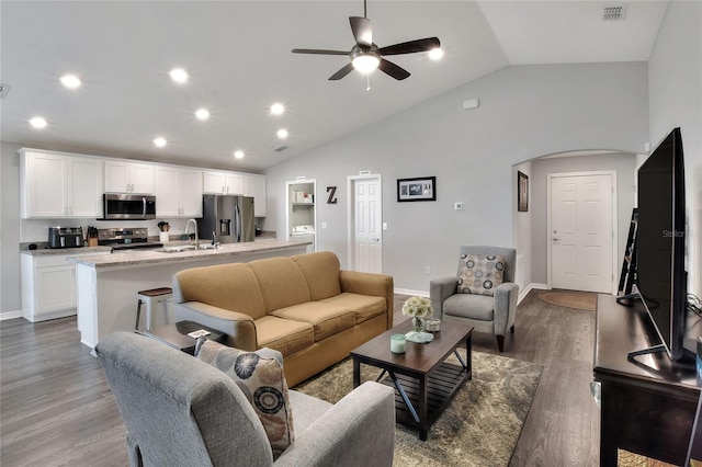 living room with ceiling fan, sink, wood-type flooring, and vaulted ceiling