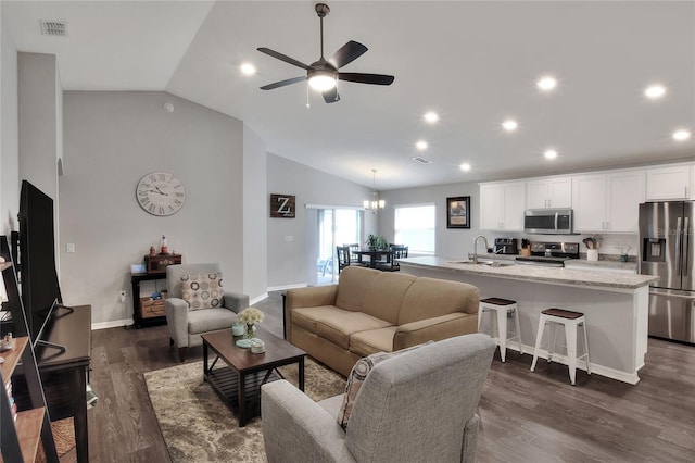 living room with ceiling fan with notable chandelier, lofted ceiling, dark wood-type flooring, and sink