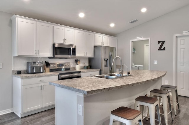 kitchen featuring appliances with stainless steel finishes, sink, white cabinetry, and an island with sink