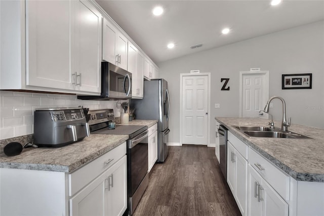 kitchen featuring sink, vaulted ceiling, dark hardwood / wood-style floors, white cabinetry, and stainless steel appliances