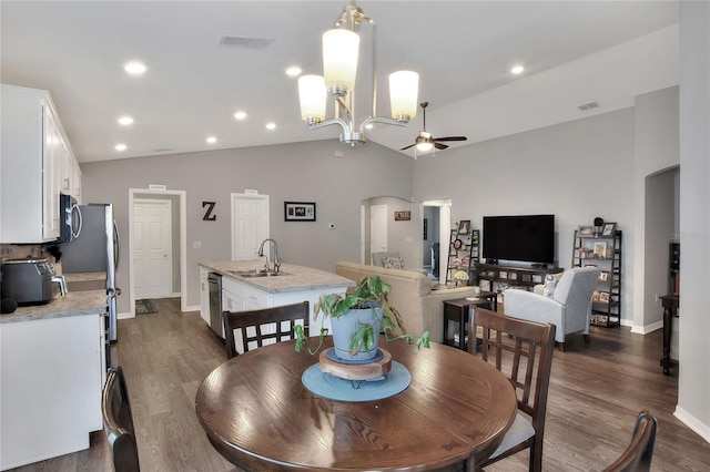 dining room featuring vaulted ceiling, dark hardwood / wood-style flooring, sink, and ceiling fan with notable chandelier