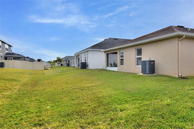 back of property featuring central air condition unit and a yard