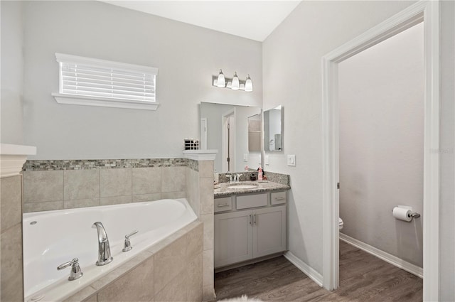 bathroom featuring hardwood / wood-style floors, vanity, toilet, and tiled tub