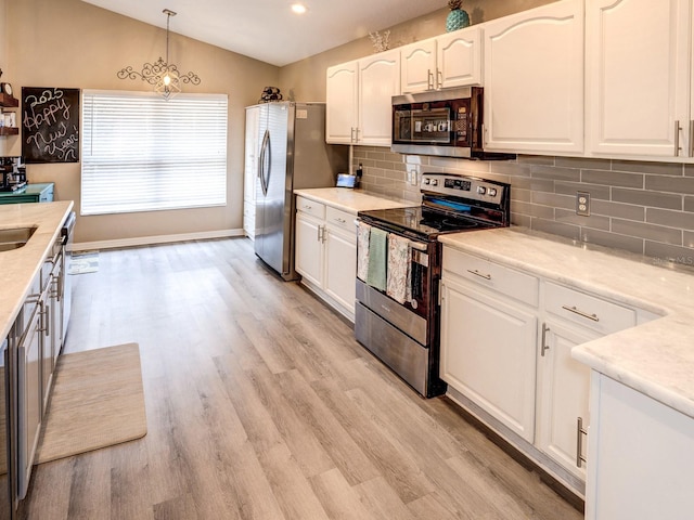 kitchen featuring stainless steel appliances, tasteful backsplash, pendant lighting, vaulted ceiling, and white cabinets