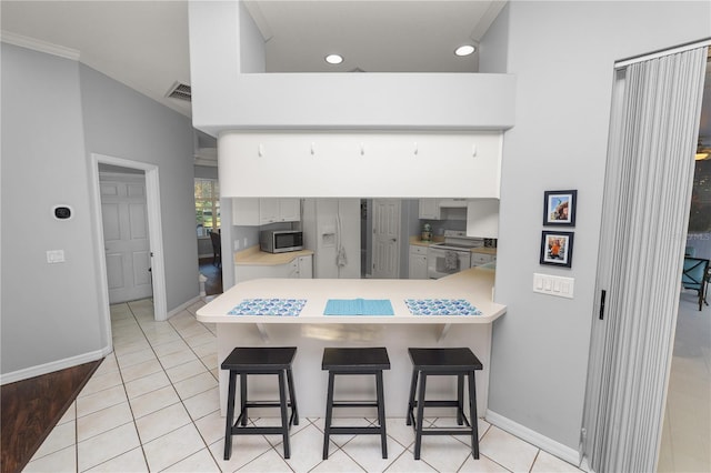 kitchen with white cabinetry, kitchen peninsula, white appliances, a breakfast bar area, and ornamental molding