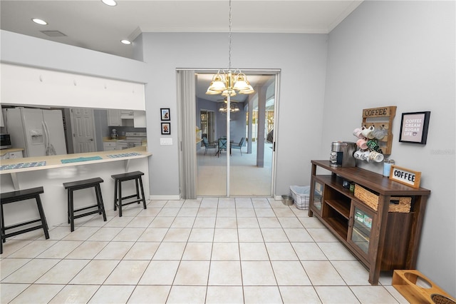 interior space with a kitchen bar, white appliances, crown molding, an inviting chandelier, and hanging light fixtures