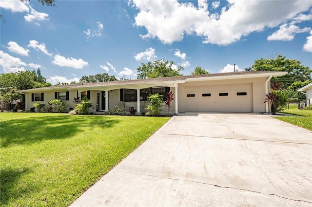 ranch-style house featuring a garage, driveway, a front lawn, and stucco siding