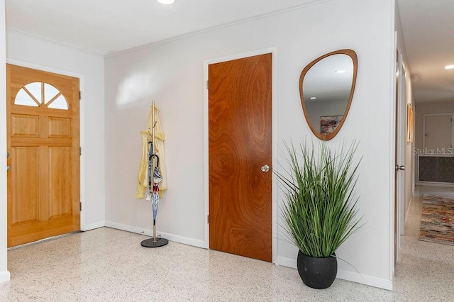 foyer featuring baseboards and speckled floor