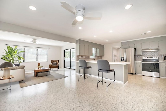 kitchen featuring open floor plan, appliances with stainless steel finishes, light speckled floor, and gray cabinetry