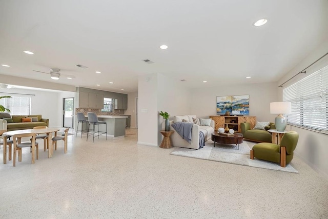 living area with a healthy amount of sunlight, visible vents, light speckled floor, and recessed lighting