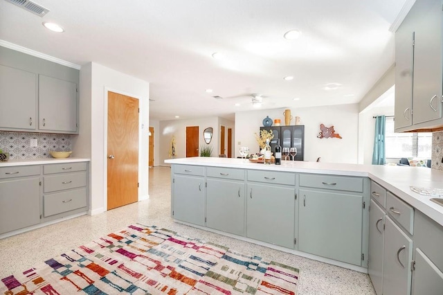 kitchen featuring light speckled floor, light countertops, visible vents, gray cabinetry, and a peninsula