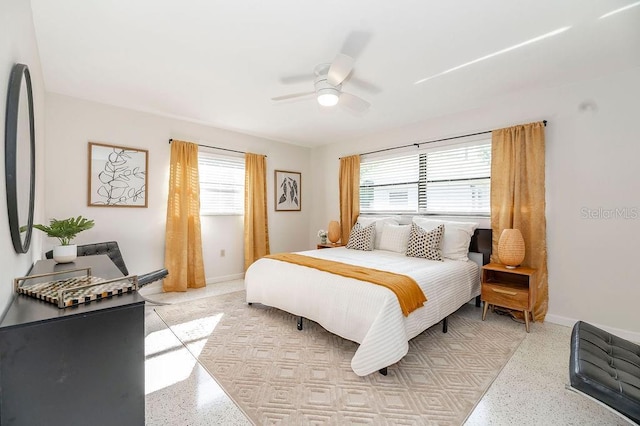 bedroom featuring ceiling fan, multiple windows, baseboards, and light speckled floor