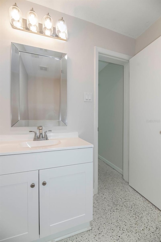 bathroom with visible vents, vanity, and speckled floor