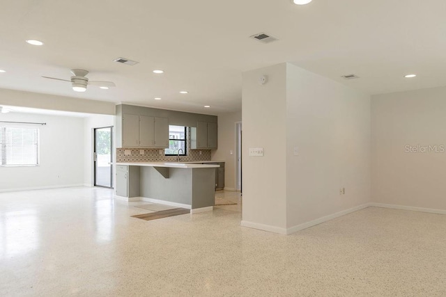 kitchen featuring light countertops, a breakfast bar, visible vents, and gray cabinetry