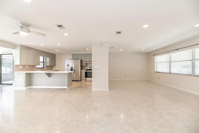 unfurnished living room with plenty of natural light, visible vents, and a ceiling fan