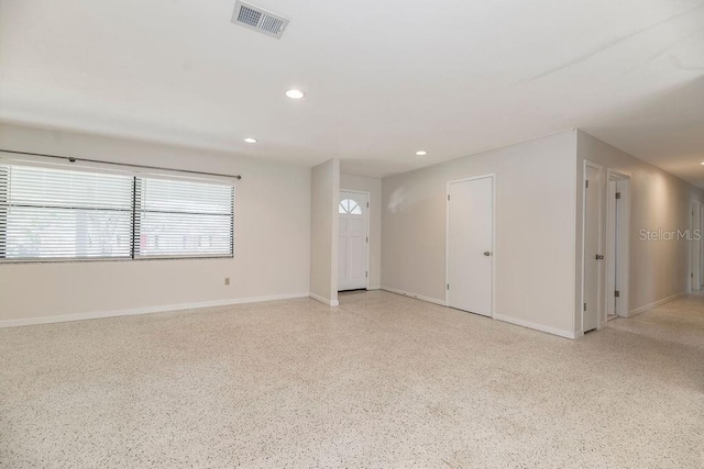 empty room featuring baseboards, visible vents, speckled floor, and recessed lighting