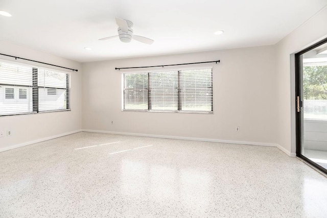 unfurnished room featuring light speckled floor, a ceiling fan, and baseboards