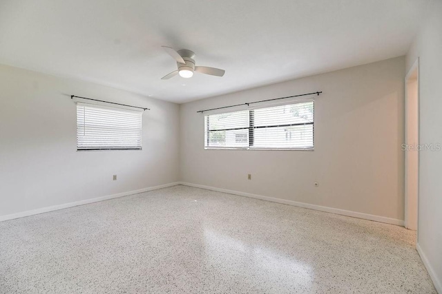 unfurnished room featuring ceiling fan, baseboards, and speckled floor