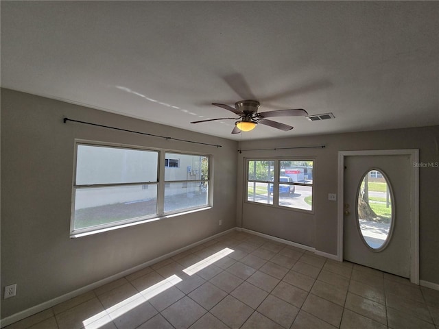 foyer entrance with baseboards, ceiling fan, visible vents, and light tile patterned floors