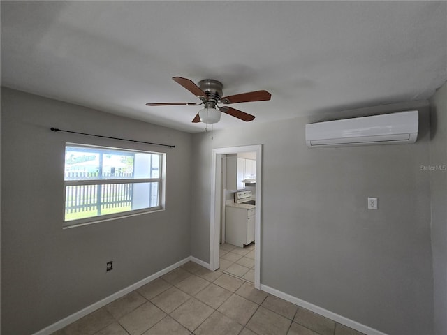 spare room featuring baseboards, a wall mounted air conditioner, ceiling fan, and light tile patterned floors